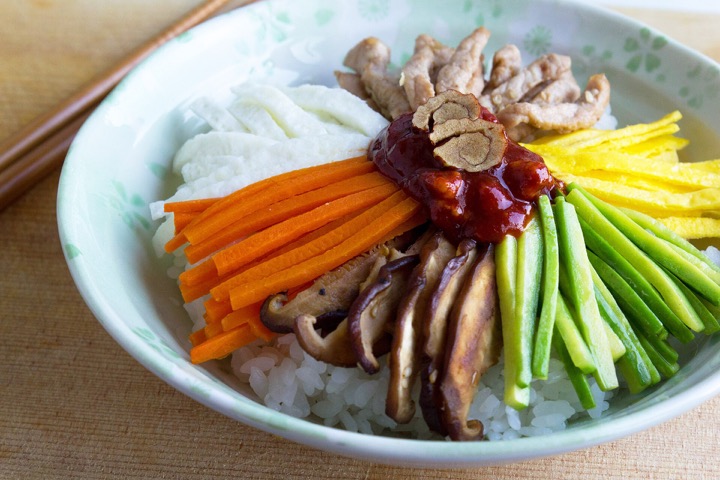 Rice, egg and assorted toppings in a bowl of bibimbap