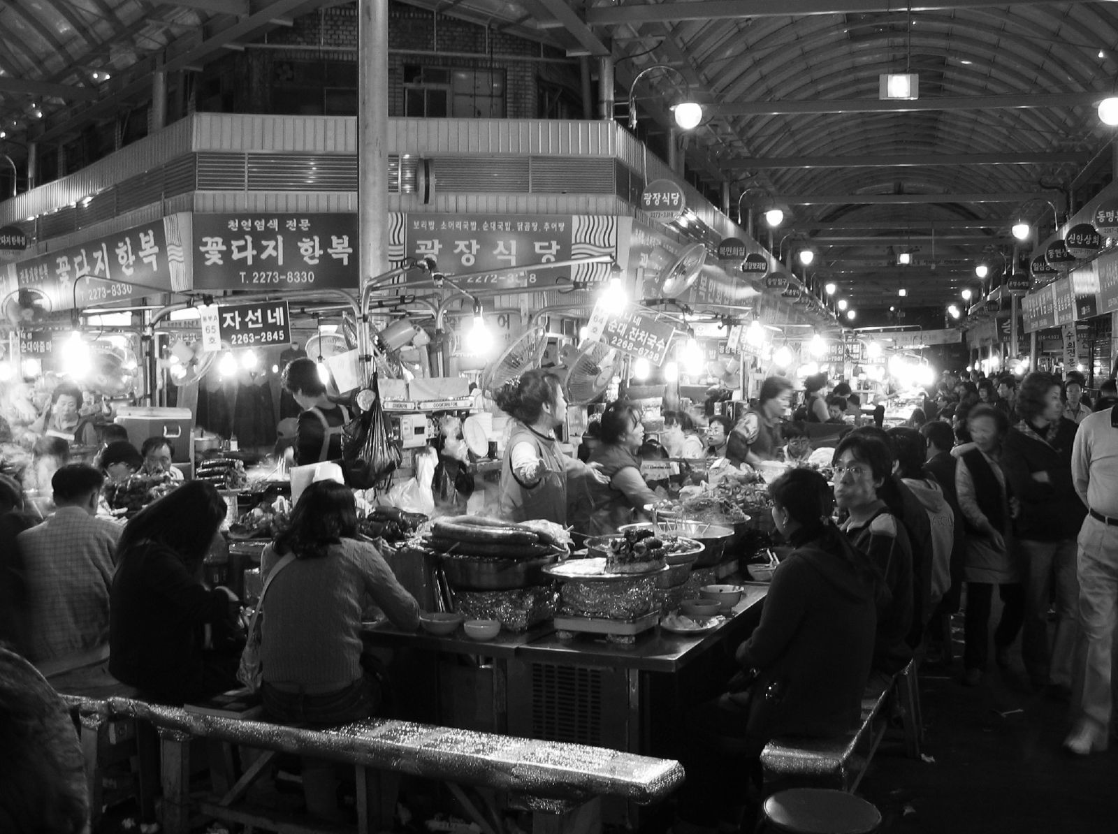 人们坐在首尔广藏市场内的餐饮柜台旁