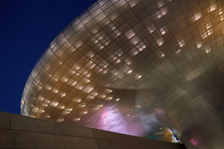 Night exterior of Dongdaemun Design Plaza with its curved silver facade illuminated