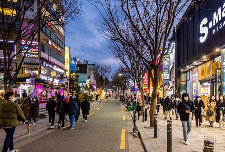 Hongdae Walking Street with shops and pedestrians at dusk